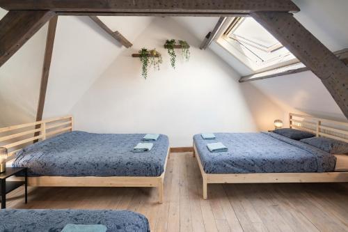 a attic room with two beds and a window at Tempel Cathedral Lodge in the Heart of Antwerp in Antwerp