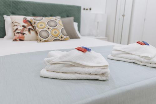 two white towels are stacked on a bed at Your Cozy Sapphire Apartment in Athens