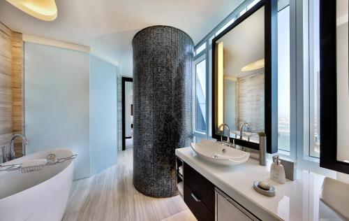 a bathroom with a tub and a sink and a bath tub at Rosewood Abu Dhabi in Abu Dhabi