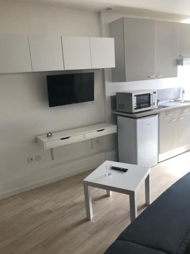 - une cuisine blanche avec une table et un four micro-ondes dans l'établissement Studio moderne au calme, à Cappelle-la-Grande