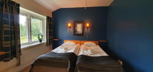 two beds in a room with a blue wall at Nipanhotellet in Sollefteå