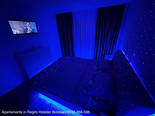 een blauwe slaapkamer met een bed en een televisie bij Apartament cu 3 camere De Lux aproape de Cornisa Aquapark vizavi de Carrefour in Botoşani