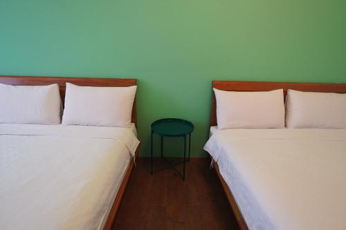 two beds in a room with a stool between them at Taitung city-cottage B&B in Taitung City