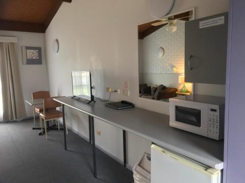 a kitchen with a counter with a microwave and a living room at Bakery Park Motor Inn in Tocumwal