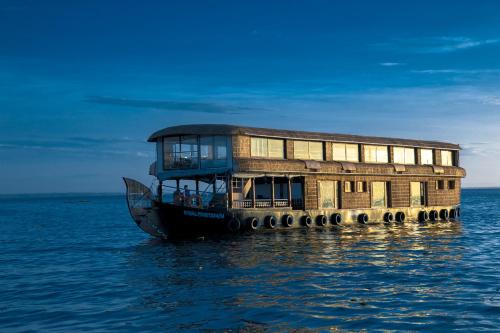 un barco en el agua con un edificio en él en Harmony Houseboats, en Alleppey