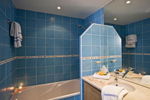 a blue tiled bathroom with a tub and a sink at Le Suffren Hôtel in Grimaud