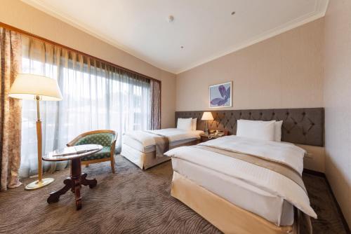 Habitación de hotel con 2 camas, escritorio y ventana en Yaward Resort - Taoyuan Golf & Country Club, en Longtan