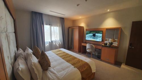 ジッダにあるAl Rayyan Towerのベッド、デスク、テレビが備わるホテルルームです。