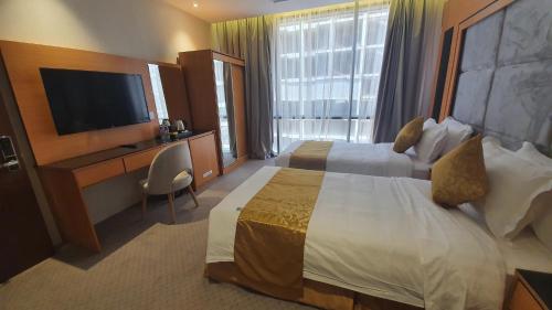 a hotel room with two beds and a flat screen tv at Al Rayyan Tower in Jeddah
