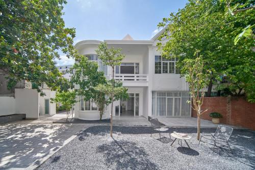 a white building with chairs and trees in front of it at M Village Living 47 Thảo Điền in Ho Chi Minh City