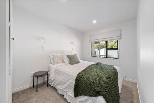 a white bedroom with a bed and a window at Peaceful Escape - Picton Holiday Apartment in Picton