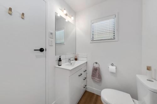 Baño blanco con lavabo y aseo en Peaceful Escape - Picton Holiday Apartment en Picton