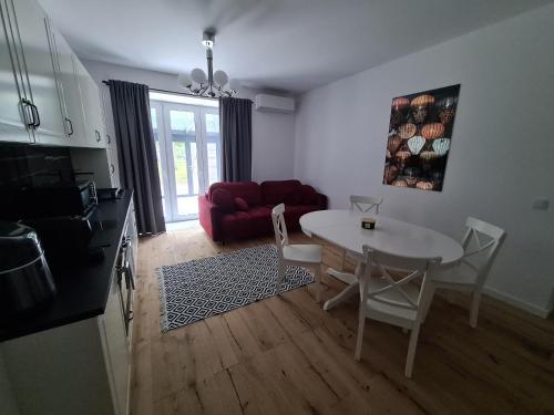 a living room with a table and a red couch at Apartamenty Osmolice w Stawach in Dęblin