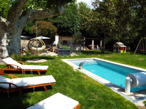 una piscina en un patio con sillas y un árbol en Gîte de Fanny du Moulin de Tartay en Avignon, en Aviñón