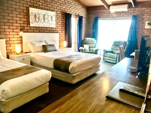 a hotel room with two beds and a desk at Bakery Park Motor Inn in Tocumwal