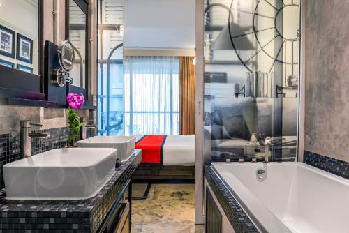 een badkamer met 2 wastafels, een bad en een bed bij Pattaya Modus Beachfront Resort in Noord Pattaya