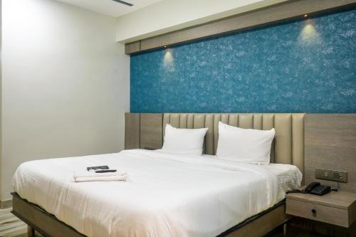 - une chambre avec un grand lit et un mur bleu dans l'établissement Hotel VR Grand, à Vizianagram City
