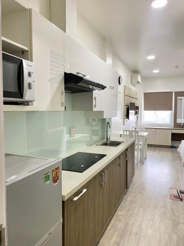 une cuisine avec des armoires blanches, un évier et un micro-ondes dans l'établissement Hotel GreenRiver, à Hô-Chi-Minh-Ville