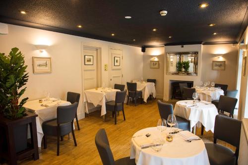 a restaurant with tables and chairs with white tablecloths at The Charlton Boutique Hotel in Cheltenham