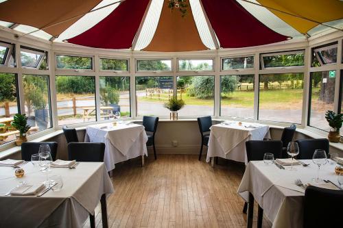 a restaurant with tables and chairs in a room with windows at The Charlton Boutique Hotel in Cheltenham