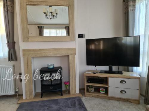 a living room with a television and a mirror at Luxury holiday lodge Lyons Robin Hood Rhyl Wales in Rhyl