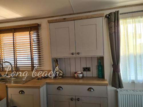 a kitchen counter with white cabinets and a window at Luxury holiday lodge Lyons Robin Hood Rhyl Wales in Rhyl