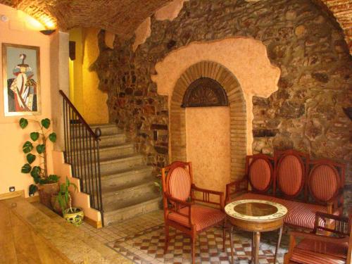 a room with a stone staircase with two chairs and a table at Hotel Don Carlos Cáceres in Cáceres