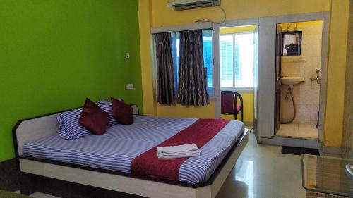 a bedroom with a bed with a green wall at Zeromiles Hotel Prasant in Digha