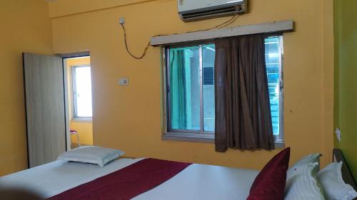 a bedroom with a bed and a window at Zeromiles Hotel Prasant in Digha