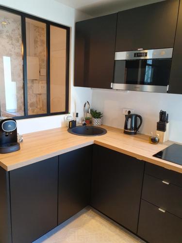 a kitchen with a sink and a microwave at LA PARENTHÈSE HAVRAISE - Parking privé Plein centre & Très calme in Le Havre