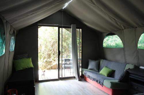 um quarto com um sofá numa tenda em The Wild - Glamping in Wilderness em Wilderness