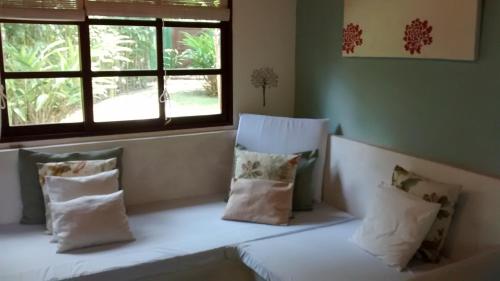 a room with a bench with pillows and a window at Chalé Charmoso in Trancoso