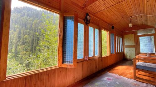 a room with large windows in a wooden house at The Misty Wilds Home, Jibhi in Jibhi