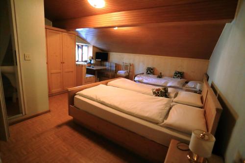 1 dormitorio con 1 cama grande con sábanas blancas en Albergo Pineta, en Castello di Fiemme