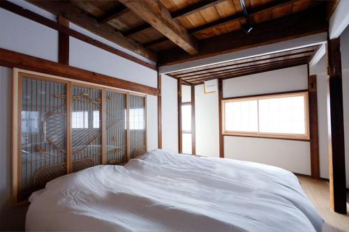 a bedroom with a white bed and two windows at 星のワルツ　御家堂(Oiedo) in Komoro
