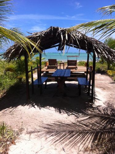 a picnic table with two benches under a straw umbrella at Villas Taturé in São Miguel dos Milagres