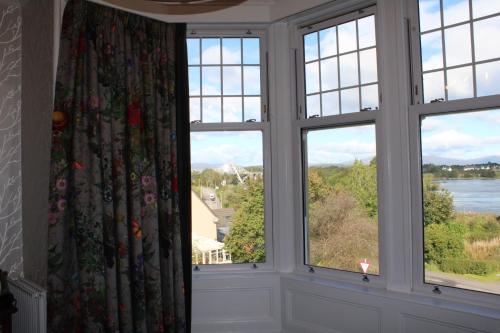 a room with three windows with a view of the water at Falls of Lora Hotel in Oban