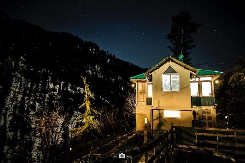 a house lit up at night in the mountains at The Misty Wilds Home, Jibhi in Jibhi