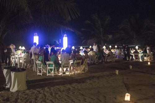 a group of people sitting at tables on the beach at night at Bambuddha Centro Holistico in Barra Vieja