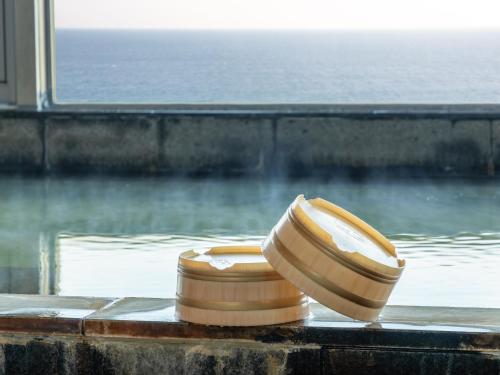two wooden bowls sitting in a bath tub with a window at Atagawa Onsen Blue Ocean in Higashiizu
