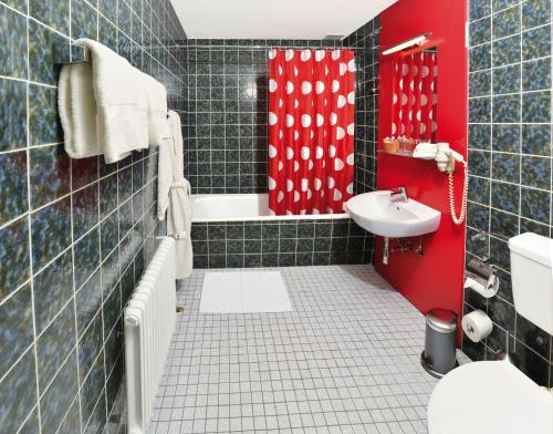 a bathroom with a red shower and a sink at Sauerland Alpin Hotel in Schmallenberg