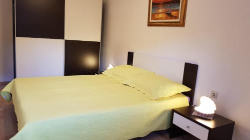 a bedroom with a bed with yellow sheets and a night stand at Apartmani Marija in Baška