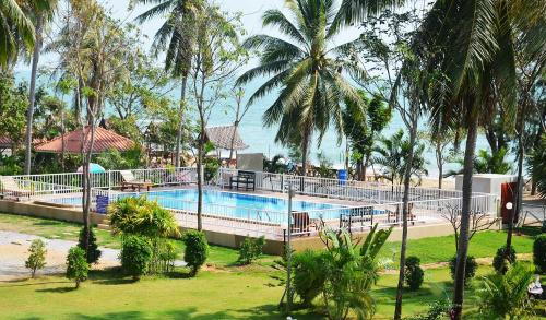 a swimming pool in a resort with palm trees at Pranmanee Beach Resort in Sam Roi Yot