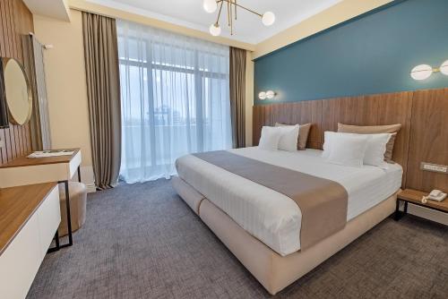 a bedroom with a large bed and a large window at Hotel Oxford in Mamaia