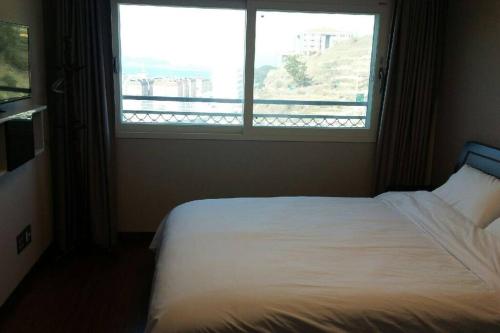 a bed in a room with a large window at Aquarius Building I 2043 in Geoje