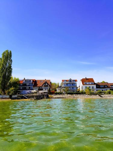a group of houses on the shore of a body of water at Birkhofer See genießen - Aparthotel am Bodensee in Immenstaad am Bodensee