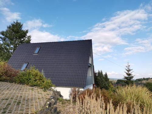 a house with a black roof on top of a hill at Ferienhaus in der Rhön Sitzmann in Bischofsheim an der Rhön