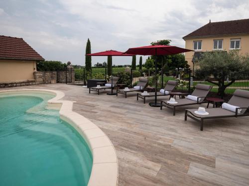 - une piscine avec des chaises et des parasols à côté d'une maison dans l'établissement La Maison de Jacqueline, à Vosne-Romanée
