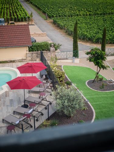 a patio with chairs and umbrellas next to a pool at La Maison de Jacqueline in Vosne-Romanée