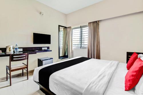 a bedroom with a bed and a desk and a television at Collection O World Class Hotel Crescent Near Phoenix Marketcity in Bangalore